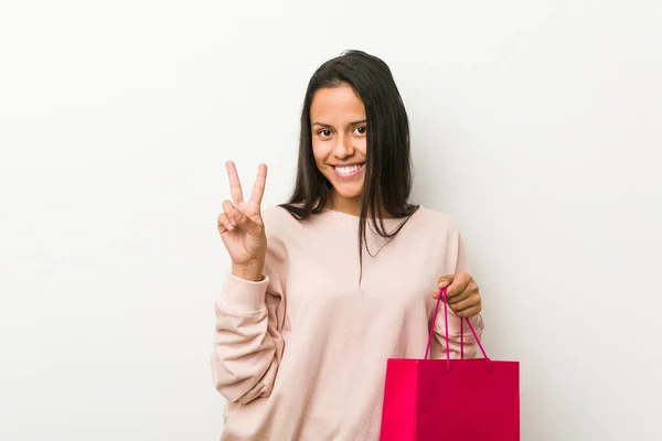 Young Hispanic Woman Holding Shopping Bag Showing Number Two Fingers — Stock Photo, Image