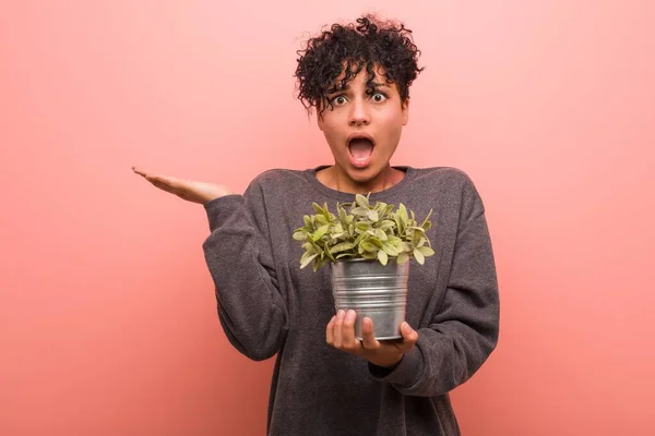 Joven Mujer Afroamericana Sosteniendo Una Planta Alegre Confiada Mostrando Gesto — Foto de Stock