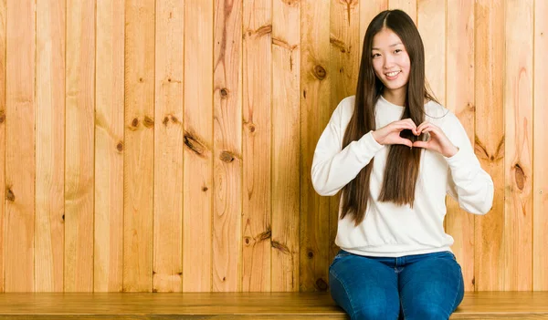 Joven Mujer China Sentada Lugar Madera Sonriendo Mostrando Una Forma —  Fotos de Stock