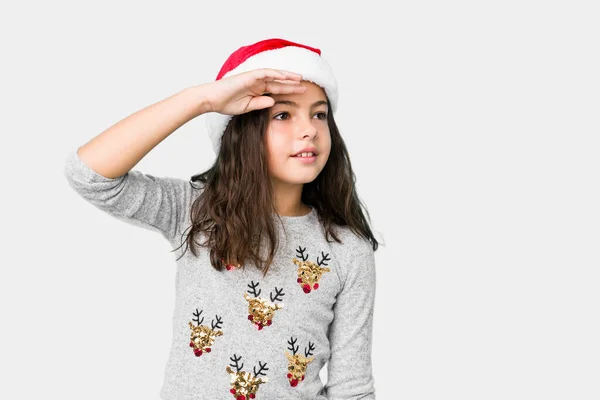 Menina Comemorando Dia Natal Olhando Para Longe Mantendo Mão Testa — Fotografia de Stock