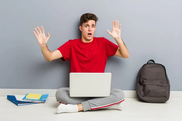 Joven estudiante sentado en el piso de su casa sosteniendo un portátil — Foto de Stock