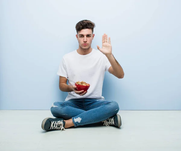 Joven Comiendo Cereales Sentado Suelo Pie Con Mano Extendida Mostrando — Foto de Stock