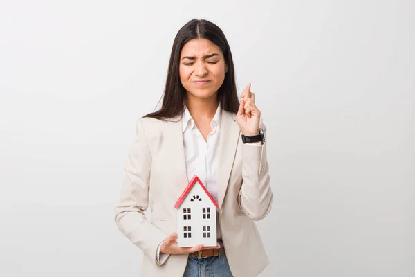 Young Arab Woman Holding House Icon Crossing Fingers Having Luck — Stock Photo, Image