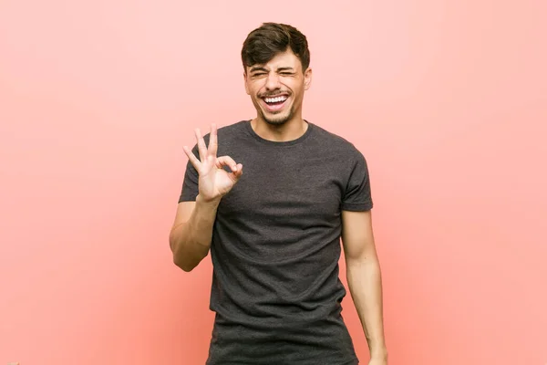 Mladý Hispánný Muž Mrká Okem Drží Ruce Dobré Gesto — Stock fotografie