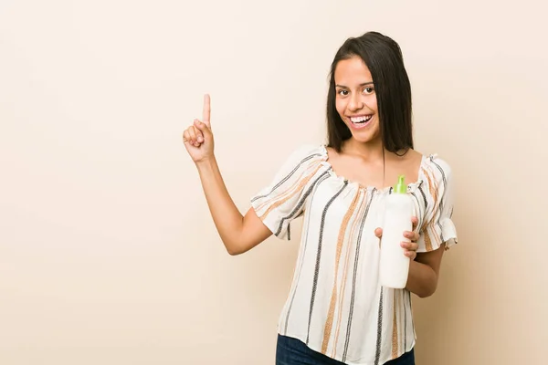 Giovane Donna Ispanica Possesso Una Bottiglia Crema Sorridente Allegramente Indicando — Foto Stock