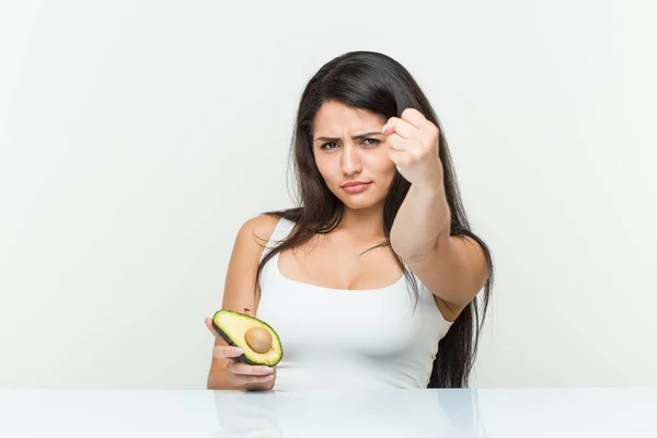 Mujer Hispana Joven Sosteniendo Aguacate Mostrando Puño Cámara Expresión Facial — Foto de Stock