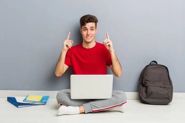 Jonge student man zittend op zijn huis vloer met een laptop — Stockfoto