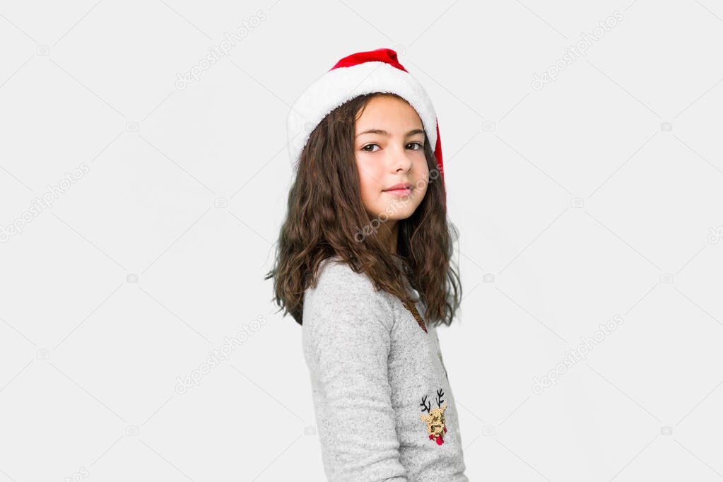 Little girl celebrating christmas day looks aside smiling, cheerful and pleasant.