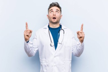 Genç, yakışıklı doktor ağzı açık bir şekilde üst tarafı işaret ediyor..