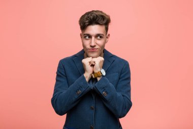 Genç iş adamı ellerini çenesinin altında tutar, mutlu bir şekilde yan tarafa bakar..