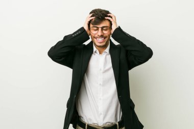 Genç İspanyol iş adamı ellerini başının üstünde tutarak neşeyle güler. Mutluluk kavramı.