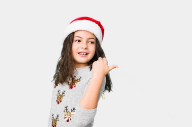 Küçük kız noel puanlarını kutluyor başparmağıyla uzakta, gülüyor ve kaygısız..