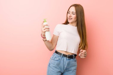 Genç beyaz kadın bir krem şişe tutan