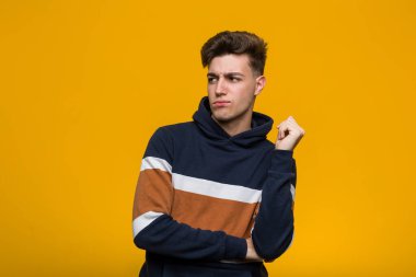 Kapüşonlu genç adam kafasının arkasına dokunuyor, düşünüyor ve bir seçim yapıyor..