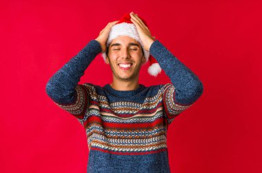 Genç adam Noel gününde gülüyor, ellerini kalbinin üstünde tutuyor, mutluluk kavramını koruyor..