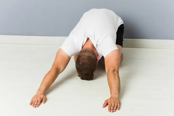 Junger kaukasischer Mann dehnt sich und praktiziert Yoga. — Stockfoto