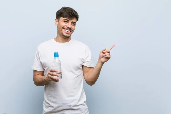 Joven Hispano Sosteniendo Una Botella Agua Sonriendo Alegremente Señalando Con — Foto de Stock