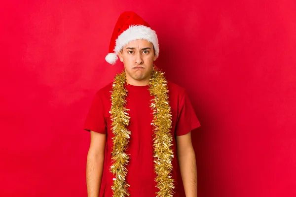 クリスマスの日に若い男が頬を吹いて 疲れた表情をしています 表情コンセプト — ストック写真
