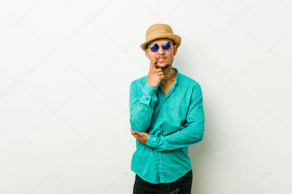 Young hispanic man wearing a summer clothes relaxed thinking about something looking at a copy space.