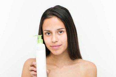 Bir nemlendirici krem şişe tutan güzel ve doğal İspanyol Genç kadın yakın