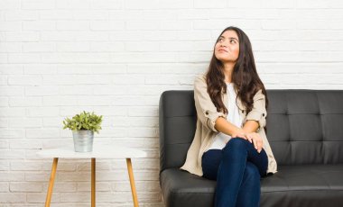 Kanepede oturan genç Arap kadın amaçlarına ve amaçlarına ulaşmayı hayal ediyor.