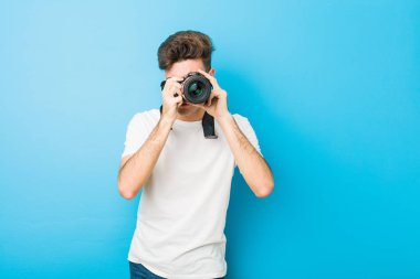 Genç beyaz adam refleks kamera ile fotoğraf çekiyor