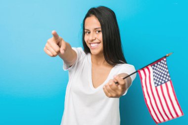 Amerika Birleşik Devletleri bayrağını tutan genç İspanyol kadın gülümsüyor..