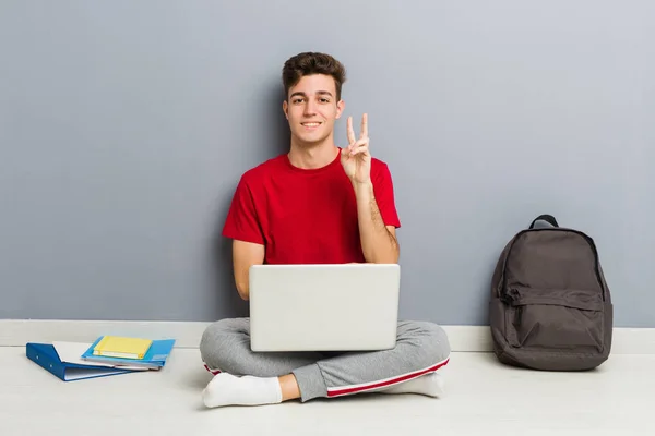 Junger Student sitzt auf dem Fußboden seines Hauses und hält einen Laptop — Stockfoto