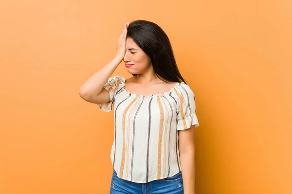 Young curvy woman forgetting something, slapping forehead with palm and closing eyes.