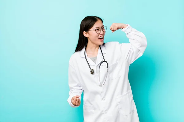 Young chinese doctor woman raising fist after a victory, winner concept.