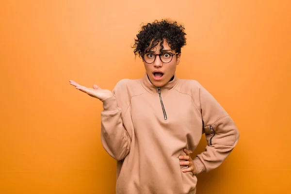 Jovem Mulher Americana Africana Mista Contra Fundo Marrom Impressionado Segurando — Fotografia de Stock