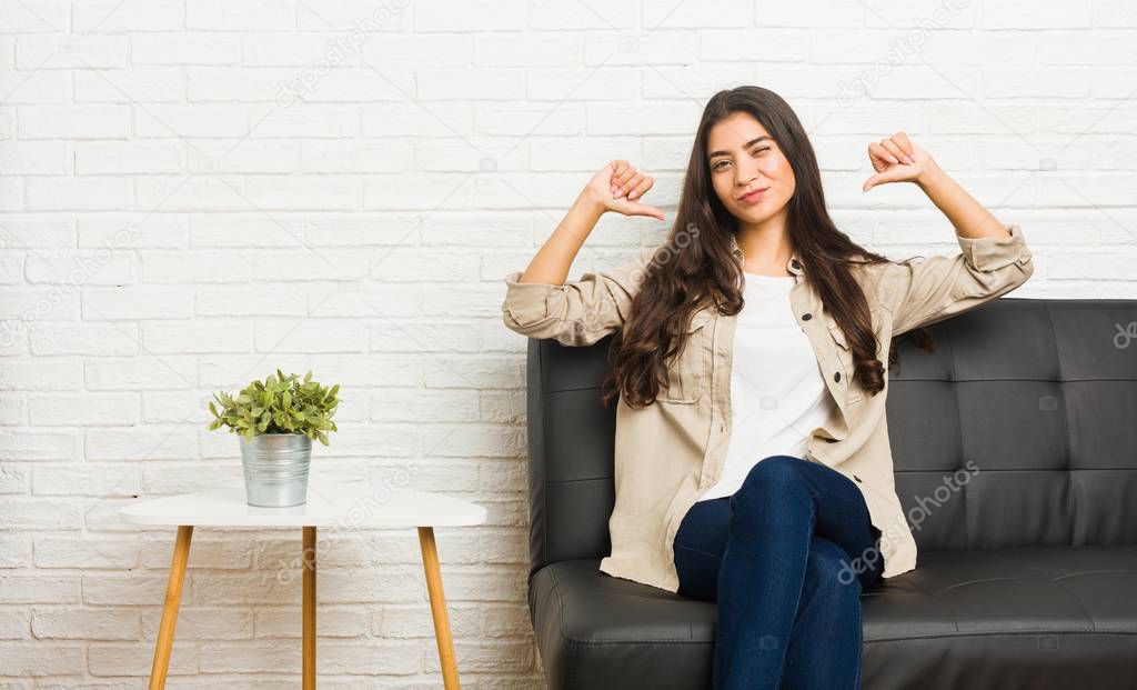 Young arab woman sitting on the sofa feels proud and self confident, example to follow.