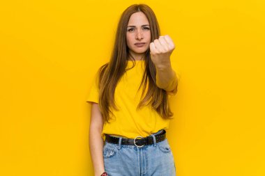 Kameraya yumruğunu gösteren kızıl saçlı genç bir kadın, agresif bir yüz ifadesi..