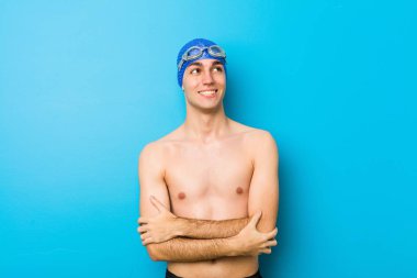 Genç yüzücü kollarını kavuşturarak gülümsüyor..