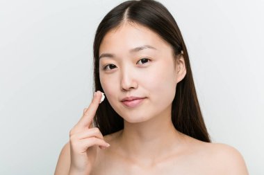 Nemlendirici krem uygulayan genç, güzel ve doğal asyalı bir kadının yakın çekim