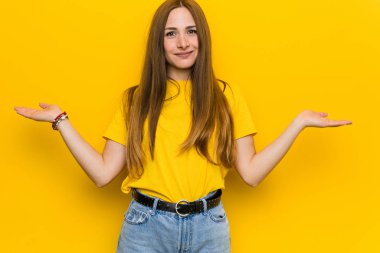 Kızıl saçlı genç kadın kollarıyla tartı yapıyor, mutlu ve kendinden emin..