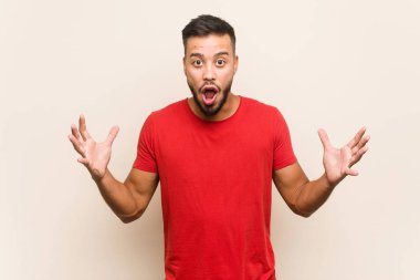 Genç Güney Asyalı bir adam zaferi ya da başarıyı kutluyor. Şaşırmış ve şok olmuş..