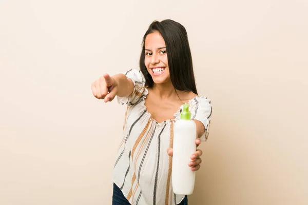 Junge Hispanische Frau Hält Eine Cremeflasche Und Lächelt Fröhlich Nach — Stockfoto