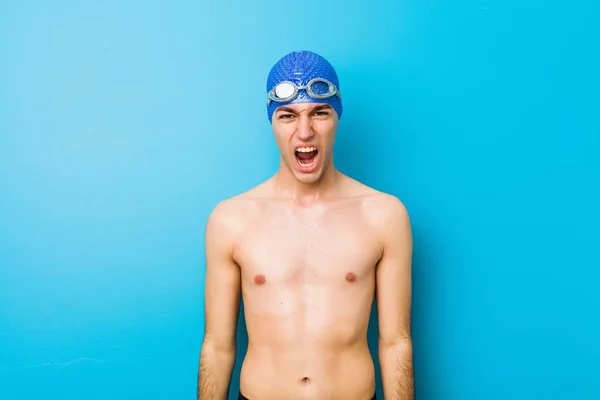 Young swimmer man screaming very angry and aggressive.