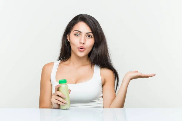 Mujer Hispana Joven Sosteniendo Una Bebida Vegetal Impresionada Sosteniendo Espacio —  Fotos de Stock