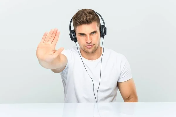 Mladý Muž Poslouchá Hudbu Sluchátka Stojí Nataženou Rukou Ukazující Stopku — Stock fotografie