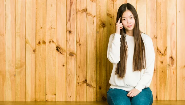 Junge Chinesin Sitzt Auf Einem Hölzernen Platz Und Zeigt Mit — Stockfoto