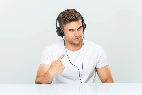 Mladý Muž Který Poslouchá Hudbu Sluchátky Ukazujícími Prstem Tebe Jako — Stock fotografie