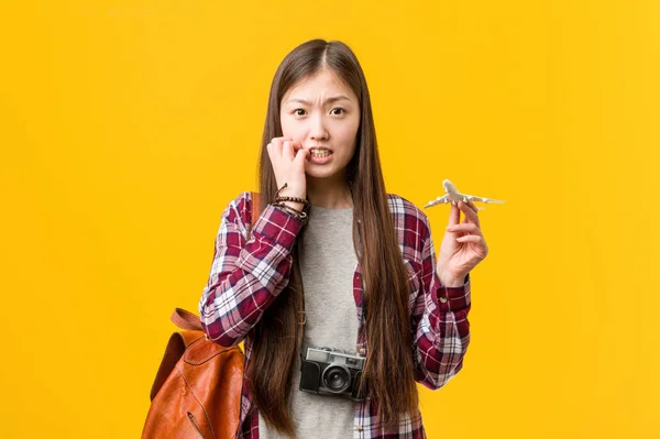 年轻的亚洲女人拿着飞机图标咬着指甲 紧张而焦虑 — 图库照片
