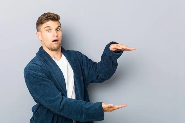 Beyaz Pijama Giyen Genç Bir Adam Ellerinin Arasında Bir Kopya — Stok fotoğraf