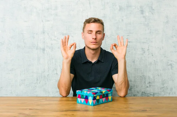 Young Caucasian Man Holding Gift Box Table Relaxes Hard Working — Stock Photo, Image