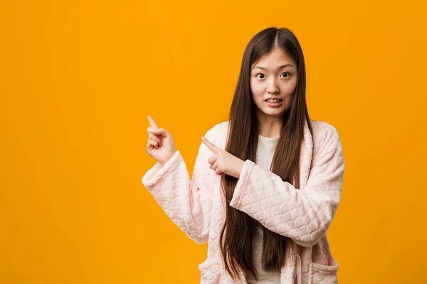 Jovem Chinesa Pijama Chocada Apontando Com Dedos Indicadores Para Espaço — Fotografia de Stock