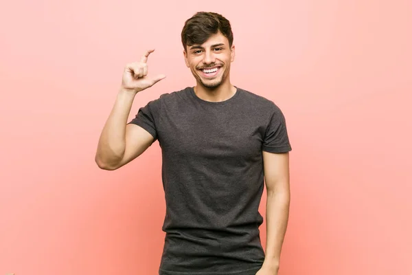 Mladý Hispánný Muž Držící Prstech Cosi Malého Usmívajícího Sebevědomého — Stock fotografie