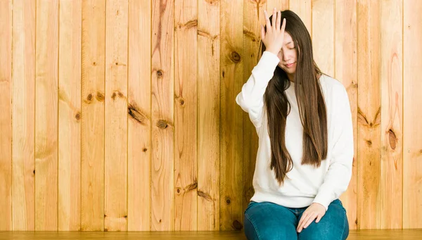 若い中国の女性は何かを忘れて木製の場所に座って 手のひらで額を平手打ちし 目を閉じる — ストック写真