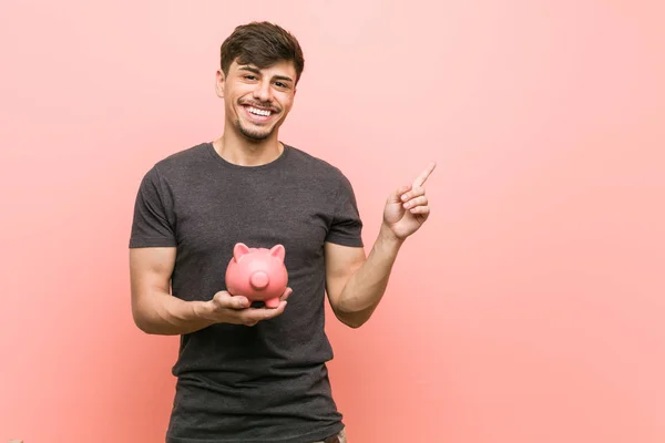 Jovem Hispânico Homem Segurando Porquinho Banco Sorrindo Alegremente Apontando Com — Fotografia de Stock